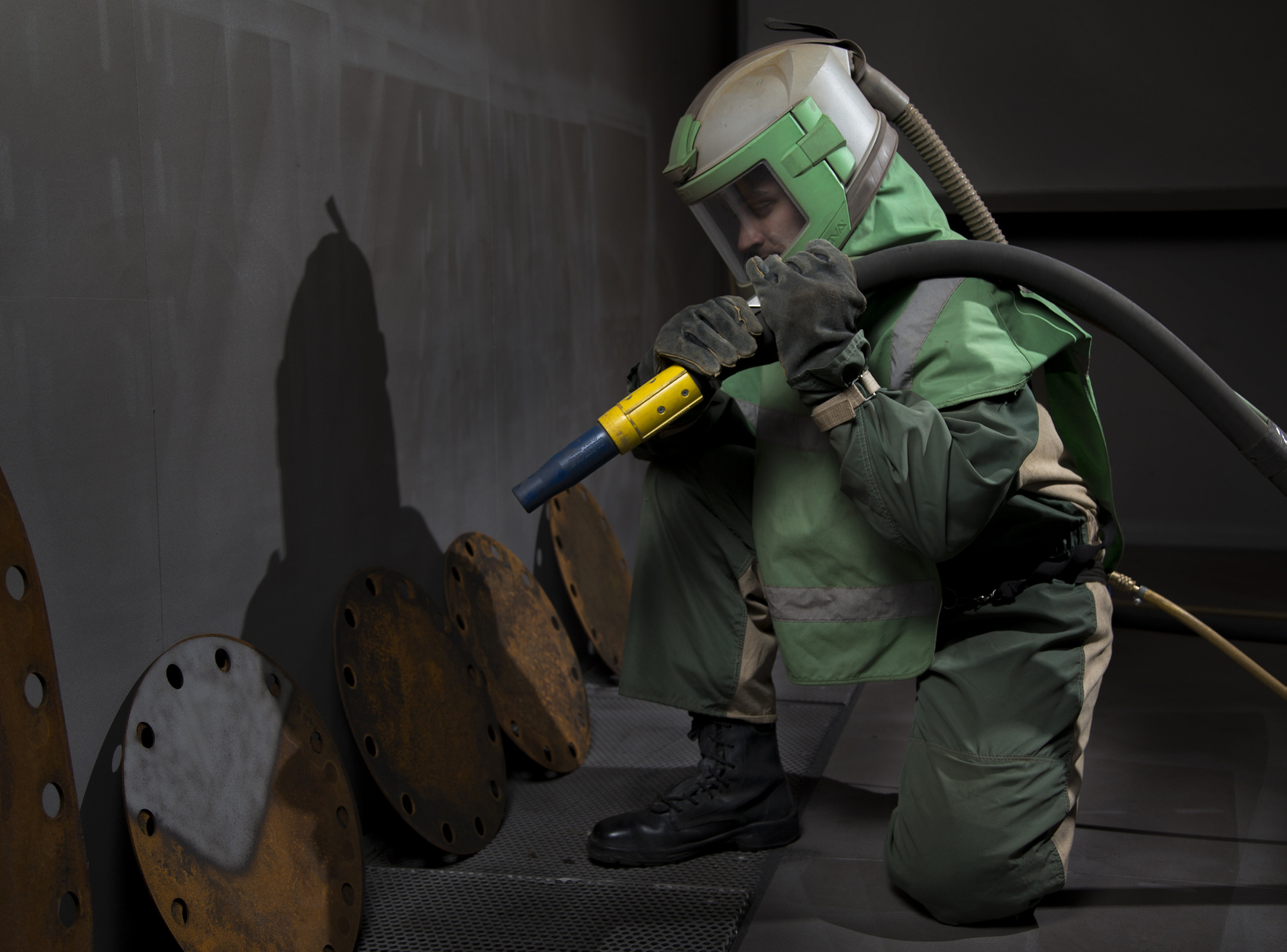 Able Seaman Boatswains Mate Alex Turner sandblasts hatch plates in preparation for painting at the HMAS Stirling Fleet Support Unit's Corrosion Control section.